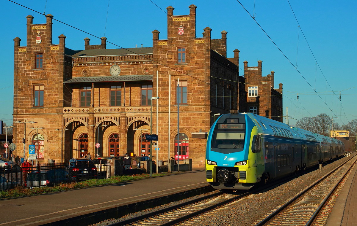 Am 29.12.2016 fährt der Stadler Kiss ET 601 der Westfalenbahn aus dem Bahnhof Minden (Westfalen) aus. Für den Betrieb auf der Strecke von Bielefeld bzw. Rheine nach Braunschweig beschaffte die Westfalenbahn 13 dieser Doppelstockzüge. Das im romantischen Stil errichtete Empfangsgebäude wurde 1848 fertiggestellt und gehört damit zu den ältesten noch erhaltenen Bahnhofsgebäuden in Deutschland. Historisch bedingt ist auch die Insellage: Westlich des Gebäudes endeten die Züge der Köln-Mindener Eisenbahn, auf der hier sichtbaren Ostseite die aus Braunschweig/Hannover kommenden Züge der Königlich Hannoverschen Staatseisenbahnen.