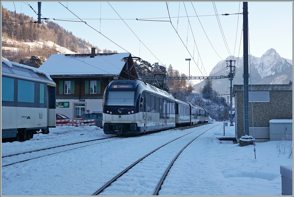 Am Schluss des GoldenPass Panoramic PE 2212 von Montreux nach Zweisimmen läuft der Alpina ABe 4/4 9303 mit. Der Zug ist hier beim halt in Rossinière zu sehen, links im Bild steht  eine MOB Panoramawagen auf einem Abstellgleis. 

11. Jan. 2021