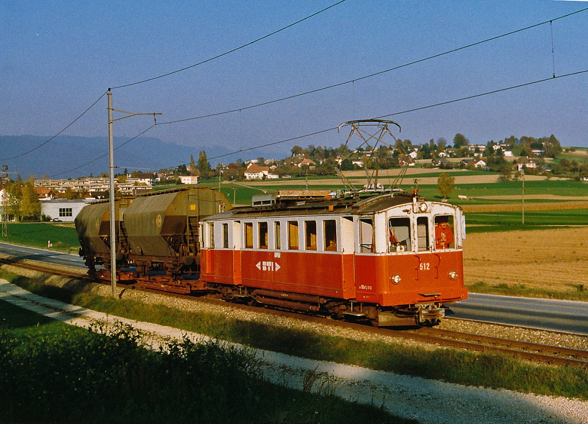 ASM/BTI: Als noch in L�scherz Getreide vom Lastwagen auf die normalspurigen Silowagen verladen wurde, verkehrten w�hrend der Getreideernte der Monate Juli und August mehrmals Rollschemelz�ge zwischen Biel und Siselen, wo die Z�ge umfahren werden mussten, um das Anschlusgeleise L�scherz mit nur einer Weiche r�ckw�rts zu bedienen. Leider wurde der Rollschemelverkehr im Dezember 2001 nach 84 Jahren eingestellt. Die Rollschemelanlage beim SBB-Bahnhof Biel musste wegen dem Bau der EXPO'02-Arteplage Biel entfernt werden. Bei Sutz wurde der BDe 4/4 12, (1916,ehemals SZB) im August 1997 im Bild festgehalten, als er zwei leere Silowagen nach L�scherz brachte. 
Foto: Walter Ruetsch
