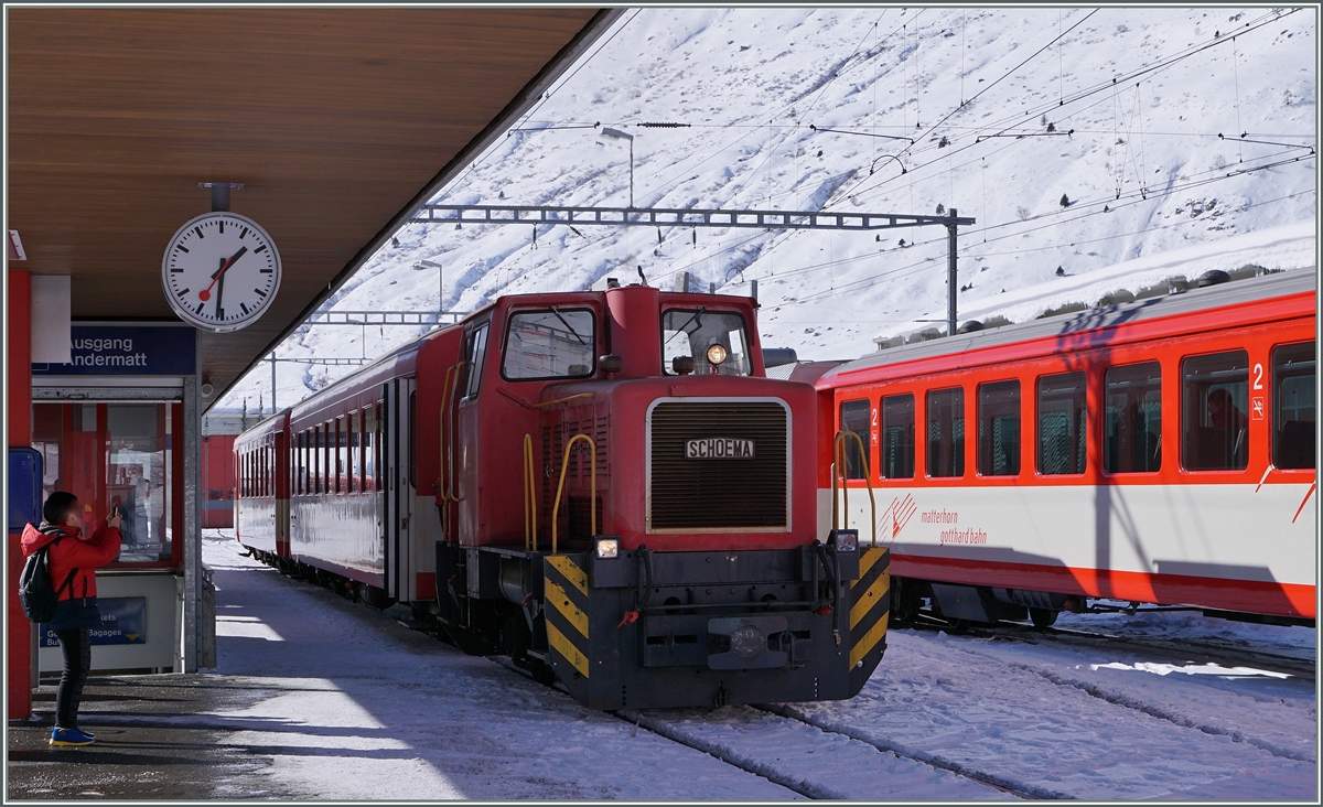 Auf der steilen Schöllenstrecke Göschenen - Andermatt ist die Beförderungslast beschränkt, so dass die MGB Regionalzüge Visp - Andermatt - Göschenen in Andermatt geschwächt, bzw. gestärkt werden. Der von Visp kommende Zug (an xx.20) lässt seine Wagen auf Gleis 3 zurück, wo sie die Rangierlok, hier die  Schöma  Tm 2/2 4971, übernimmt und an den Gegenzug (ab xx.37), rechts im Bild auf Gleis vier, manöveriert. 
11. Feb. 2016