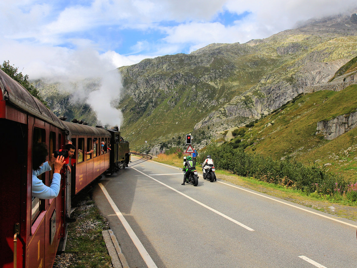 Dampfbahn Furka Bergstrecke: Der Strassenübergang zwischen Muttbach und Gletsch geschieht ohne Zahnstange, während der Verkehr warten muss. 23.August 2020 