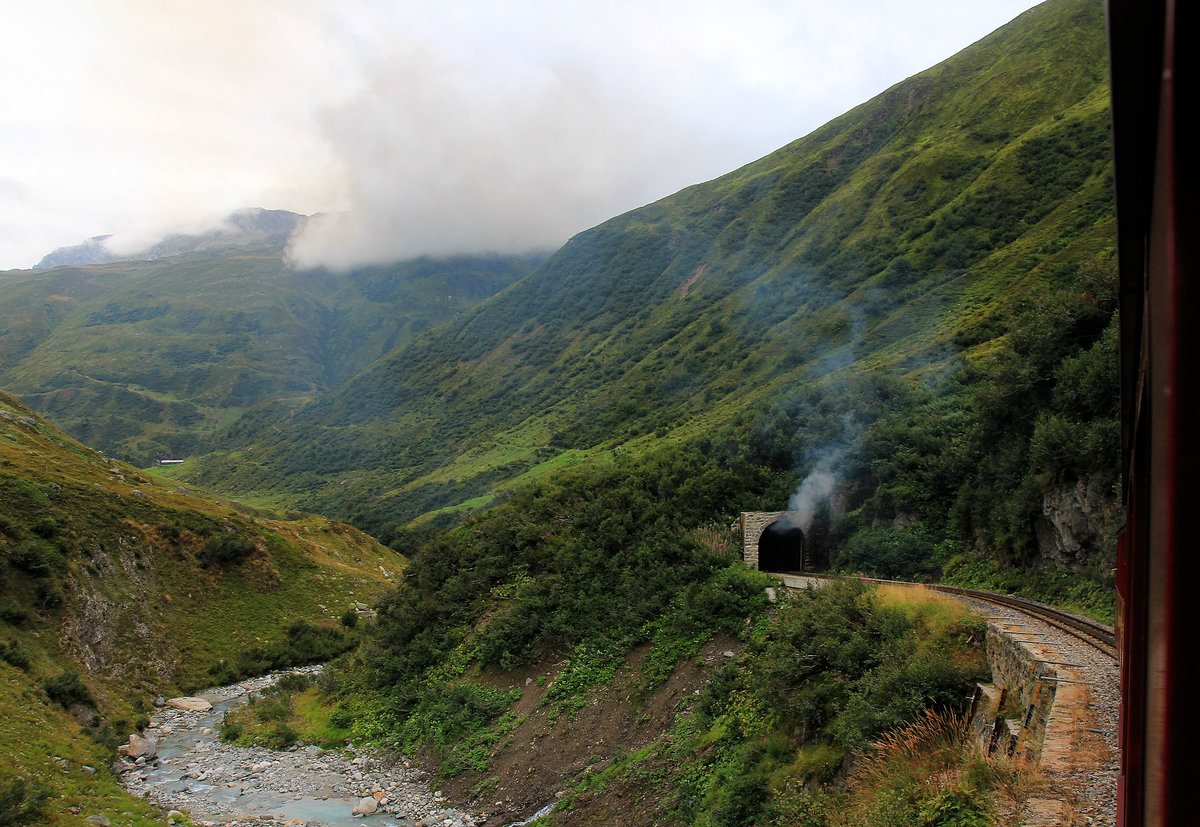 Dampfbahn Furka Bergstrecke: Faszination Dampfbetrieb - lange nachdem der Zug den Tunnel durchfahren hat, strömt noch der Qualm aus ihm. Im Aufstieg Realp - Tiefenbach. 23.August 2020 