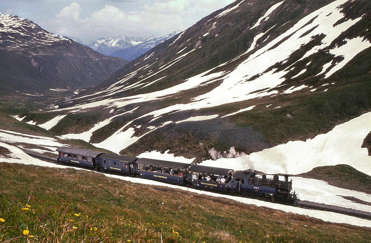 Dampfbahn Furka Bergstrecke: Lok 1 mit ihrem Zug unterhalb der Station Furka. Der zweitletzte Wagen ist der interessante AB2 2420. 1.Juli 1995 