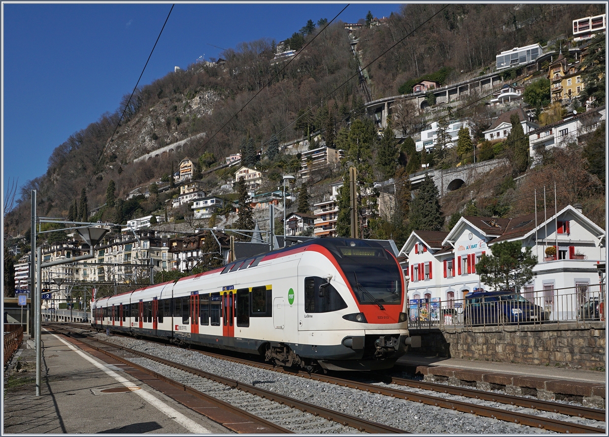 Der FLIRT 523 013 als S2 auf der Fahrt nach Villeneuve beim Halt in Territet. In der Bildmitte deutet die markante Bogenmauer den Verlauf der Rochers de Naye Bahn an, und auch die Standseilbahn von Territet nach Glion ist zu erkennen. 
27. Feb. 2017