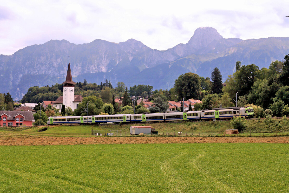 Die BLS-NPZ Z�ge werden nicht mehr lange im Einsatz stehen. Hier f�hrt ein Zug der S4 den Hang hinunter von Seftigen nach Uetendorf auf der G�rbetalstrecke; Blick aufs Stockhorn und auf die Kirche von Uetendorf. Die Fahrzeuge sind Steuerwagen ABt 80 35 962 + der NPZ Zwischenwagen 22 35 519 + der Jumbo-Doppelwagen 20 35 615 + NPZ Triebwagen 722. 8.August 2023  