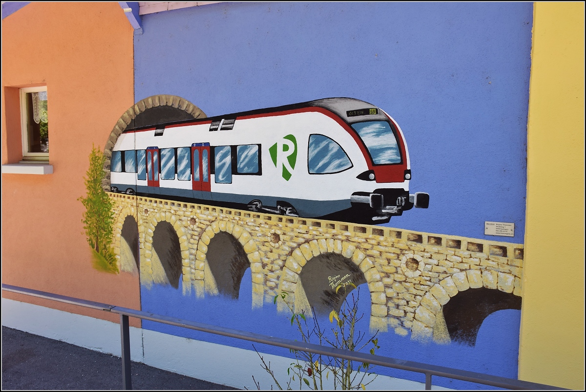 Die Umleitungen über das Läufelfingerli ziehen natürlich den Fotografen an die Strecke zur Erkundung. Da fällte einem in Sommerau das Kleinod von Régine Thommen  an den Stationsgebäuden auf. Ein Flirt, der zwar nicht auf der Linie fährt, aber mit dem  Emblem ein klares Bekenntnis zur S-Bahn Basel, die von den Verantwortlichen gegen die Bevölkerung nicht abgeschafft werden konnte. Die Webseite der Künstlerin findet sich unter http://www.thomregine.ch , wo auch weitere Werke von ihr gezeigt sind. Das Bild darf mit ihrem freundlichen Einverständnis hier gezeigt werden. Sommerau, August 2018.