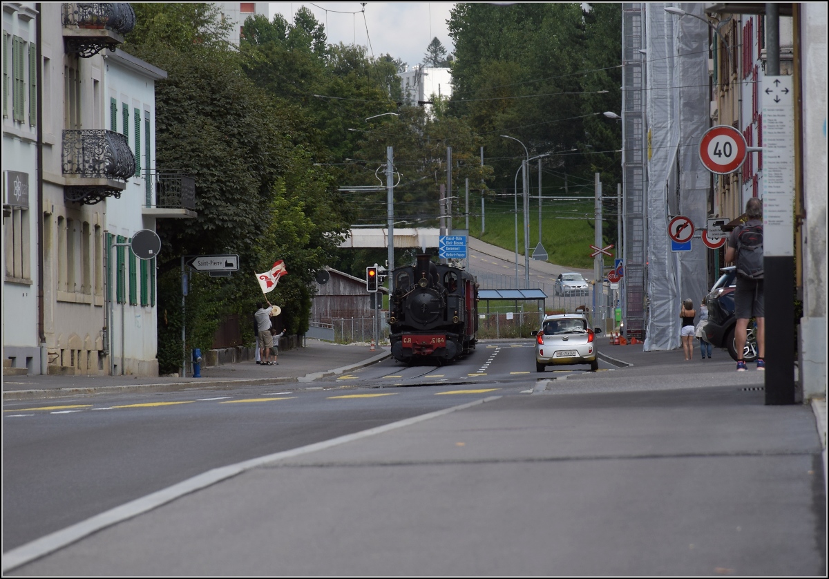 Eine etwas ungewöhnliche Verkehrsteilnehmerin in La Chaux-de-Fonds. 

CP E 164, heute bei La Traction, hat ihren jährlichen Einsatz auf der Strasse und wird von einem Fahnenschwinger mit der jurassischen Fahne im Kanton Neuenburg begrüsst. September 2021.
