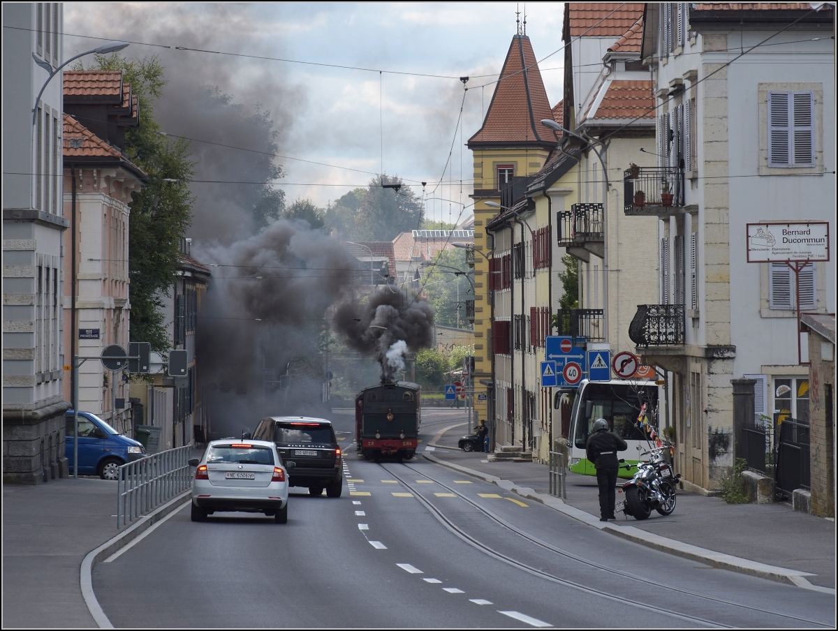 Eine etwas ungewöhnliche Verkehrsteilnehmerin in La Chaux-de-Fonds. 

Um die Kurve gefahren und schon rette sich, wer kann. Denn CP E 164, heute bei La Traction, schnaubt mit viel Rauch als Geisterfahrerin die Rue du Manège hinauf. So sammeln sich respektvoll immer mehr Autofahrer auf der falschen Strassenseite. September 2021.