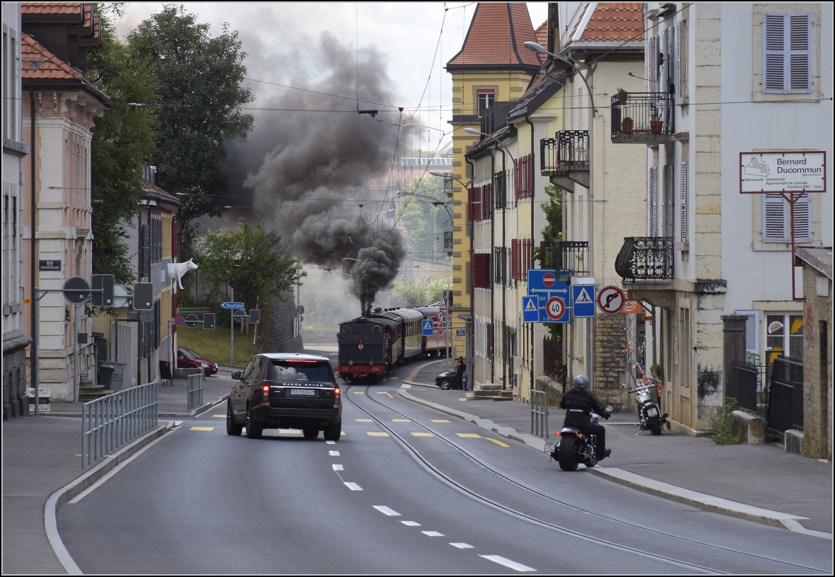 Eine etwas ungewöhnliche Verkehrsteilnehmerin in La Chaux-de-Fonds. 

Um die Kurve gefahren und schon rette sich, wer kann. Denn CP E 164, heute bei La Traction, schnaubt mit viel Rauch als Geisterfahrerin die Rue du Manège hinauf. September 2021.
