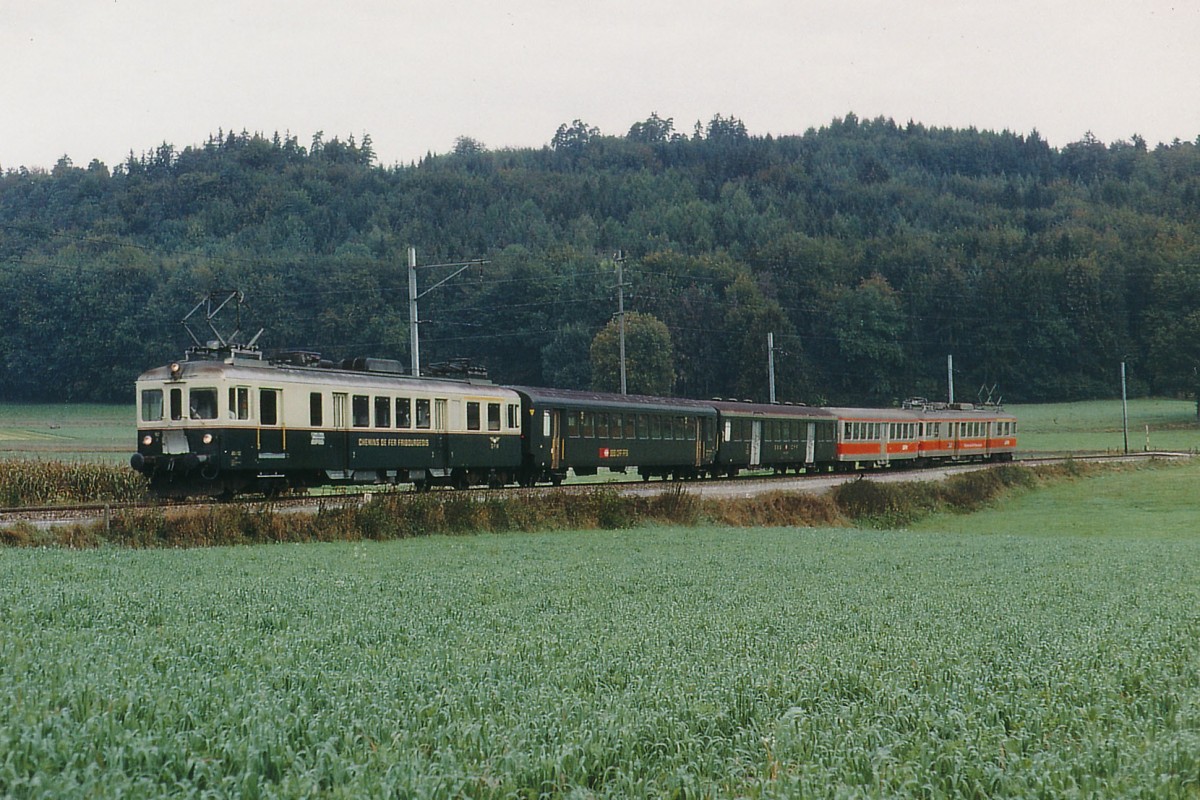 GFM/TPF: SBB Personenwagen auf Privatbahnen. Der allj�hrlich im Monat Oktober stattfindende Murtenlauf f�hrt noch immer zu einem ausserge�hnlichen Grosskampftag. Im Jahre 1971 pendelte an diesem bsonderen Anlass ein spezieller Pendelzug bestehend aus zwei ABDe 4/4 an beiden Enden sowie dem alten GFM-Mitteleinstiegwagen und zwei Verst�rkungswagen der SBB zwischen Fribourg und damals noch Ins hin und her. Die Aufnahme ist zwischen Courtepin und Pensier entstanden.
Foto: Walter Ruetsch 