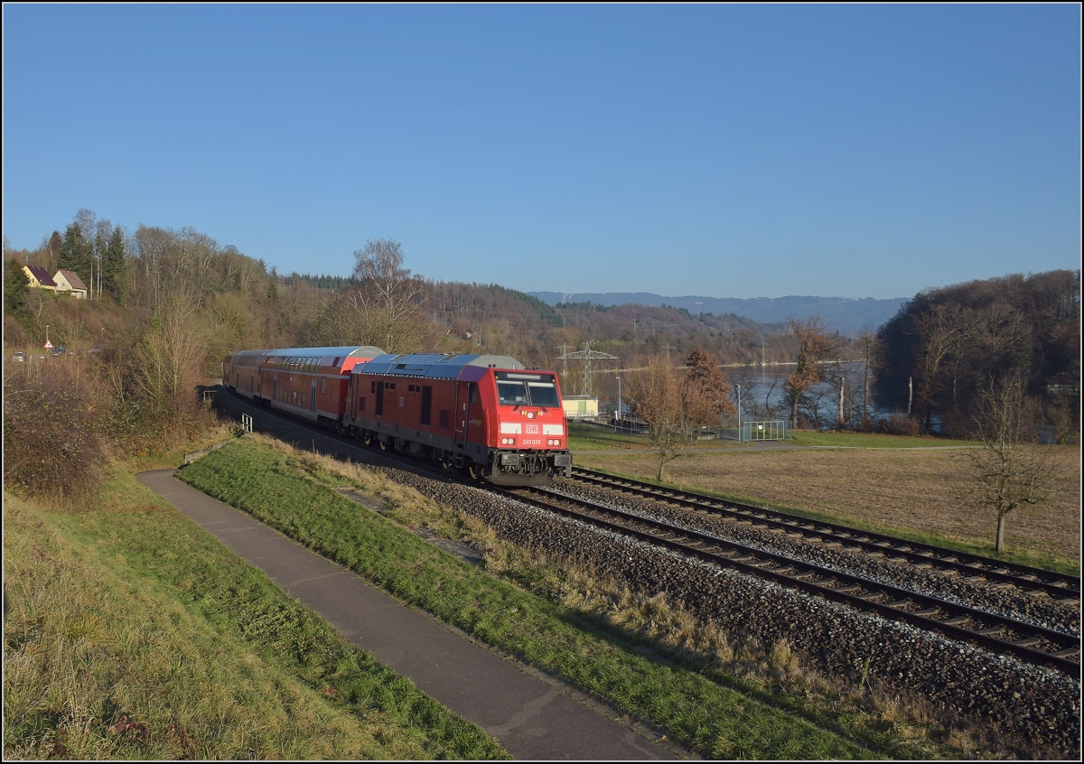 Godot-Express rechts des Hochrheins.

245 035 mit 3 Dostos. Karsau, Dezember 2021.

An jeder Station wird neuerdings erneut auf Godot gewartet. Er könnte ja noch kommen, auch wenn ihn bis heute niemand gesehen hat. Reisen im 612 war gestern, heute heißt es durch die Landschaft bummeln. Immerhin kann man besser spazieren schauen. Beachtenswert noch: Der Dosto an der Lok ist ohne Klimaanlage. Keine gute Idee am Hochrhein, wo die Sonne am Mittag die Wagen auf der Breitseite maximal aufheizt. Innen sehen die Wagen maximal dreckig aus, dagegen sind die 15 Jahre alten Schwarzwaldbahndostos hausfrauengepflegt... In der ersten Woche war bereits eine 245 nicht einsatzbereit und die vorgeblich so unzuverlässigen 612er mussten mit einer Solotraktion aushelfen.
