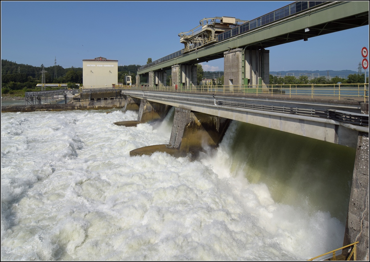 Hochwasser am Hochrhein.

Durch die Flutwehre des Kraftwerk Ryburg-Schwörstadt rauscht mehr Wasser am Kraftwerk vorbei (Aufnahmezeitpunkt ca. 1000 m²/s), als am Rheinfall zur gleichen Zeit herunterstürzt. Entsprechend laut ist das Getöse. Trotzdem hört man den 612 auf der deutschen Seite ganz deutlich. Möhlin, Juli 2021. 