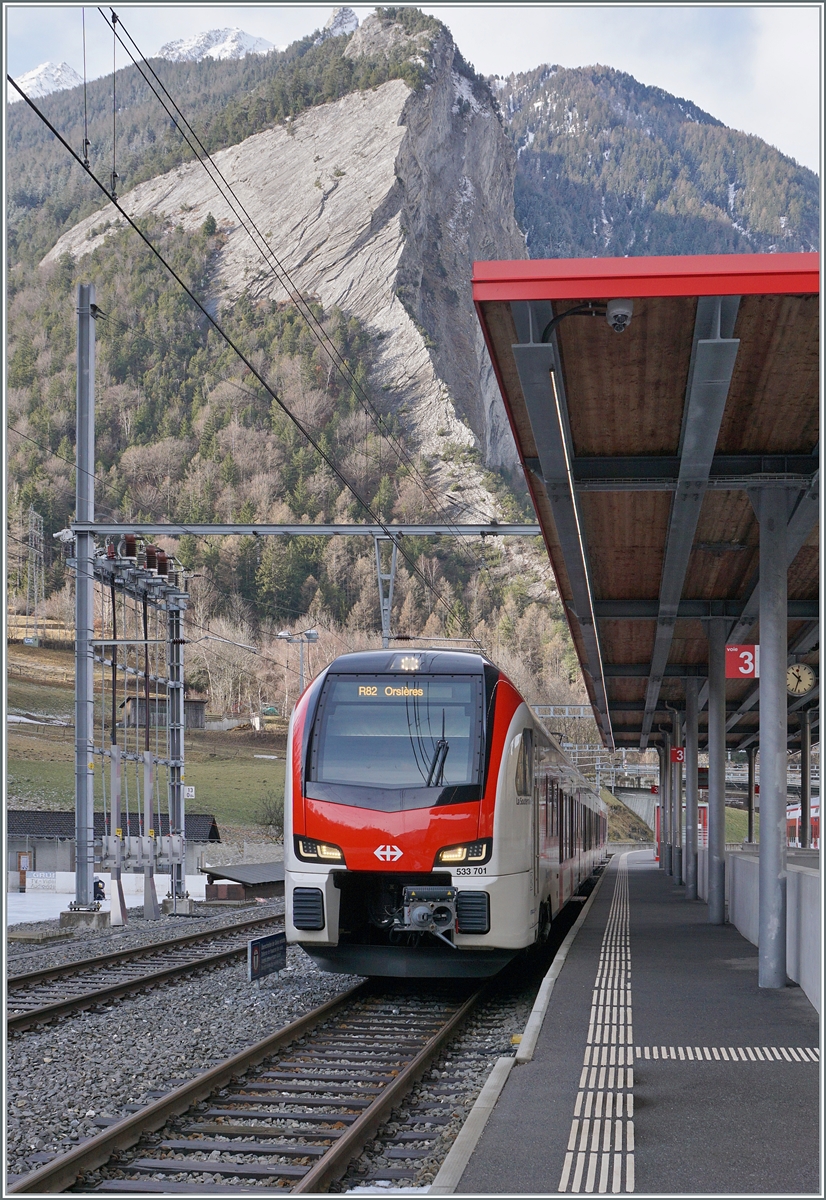 In Sembrancher wartet neue RABe 533 701 als R82 26318 auf die Abfahrt (10:34) nach Orsières. 
Der neue Region Alps RABe 533 701 mit dem Wappen der  Commune de St Léonard  und dem Namen  La Souterraine  trägt die UIC Nummer RABe 94 85 0 533 701-4 CH-RA.

24. Jan. 2026