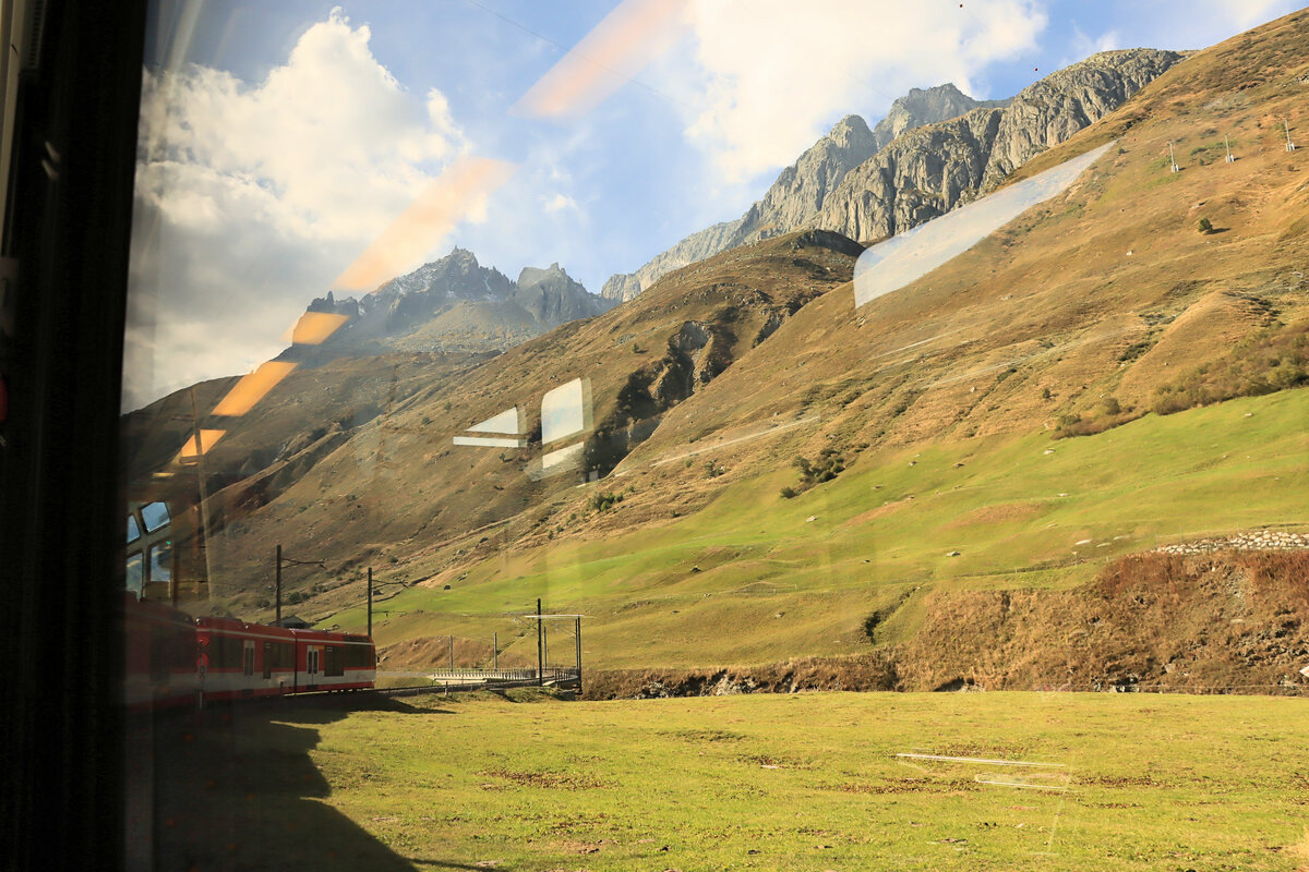 Ist jetzt das das neue Fahrvergügen auf der MGB? Aus dem Käfig heraus voller Spiegelungen ein Zug zwischen Hospental und Realp. An diesem Tag bin ich auch in einem  normalen  Reisezugwagen gefahren, und fast alle Fahrgäste öffneten von Zeit zu Zeit die Fenster, um die imposante Landschaft per Bild oder Video aufzunehmen. 21.September 2022 