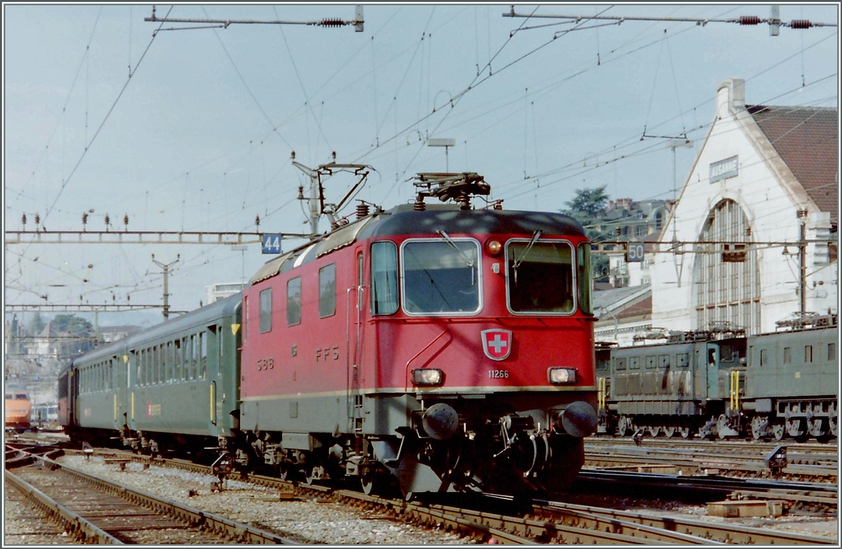 Lange Zeit bewährter Alltagsverkehr: Re 4/4 II 11266 mit EW I bzw. EW II im Schnellzugsverkehr. 
Hier erreicht die Re 4/4 II mit einem Schnellzug den Bahnhof Lausanne. 
Leider nur angescchnitten ist links noch ein TGV zu erkennen und rechts zwei mal zwei Ae 4//, die auf ihren abendlichen Güterzugseinsatz warten.
(Gescanntes Foto)
März 1994