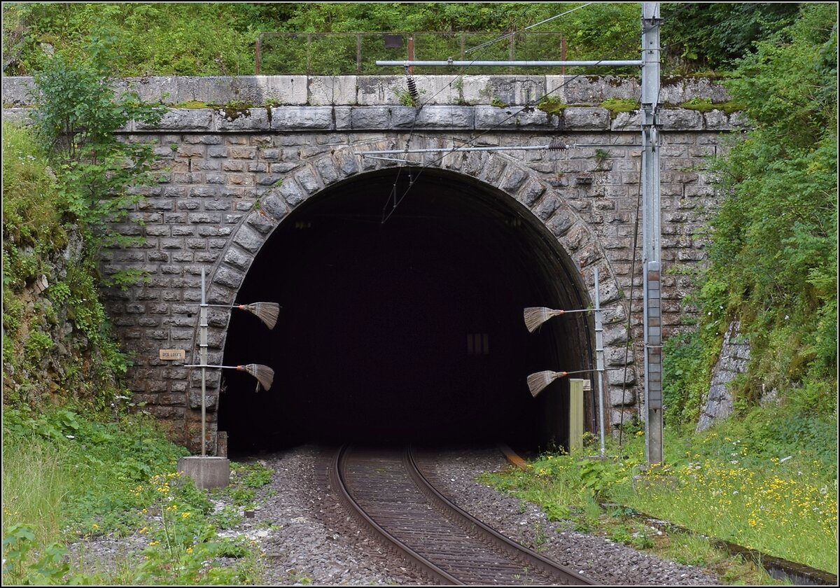 Mal eine technische Kuriosität statt bunter Bilder.

Die Strecke von Neuenburg nach La Chaux-de-Fonds brauchte einen langen Scheiteltunnel unter dem Col de la Vue des Alpes. Da offenbar einfacher zu realisieren, gab es in Convers einen Zwischenangriff und eine leicht verlängerte Strecke. Hier das Tunnelportal des Des Loges Tunnels. Dann folgt eine 125 m lange Kurve in den nächsten Tunnel. Les Convers, Juli 2018.

Vom anderen Tunnelportal zeigt Stefan eine Aufnahme: http://igschieneschweiz.startbilder.de/bild/schweiz~e-loks~re-465-bls-2/711292/die-bls-re-465-002-ist.html