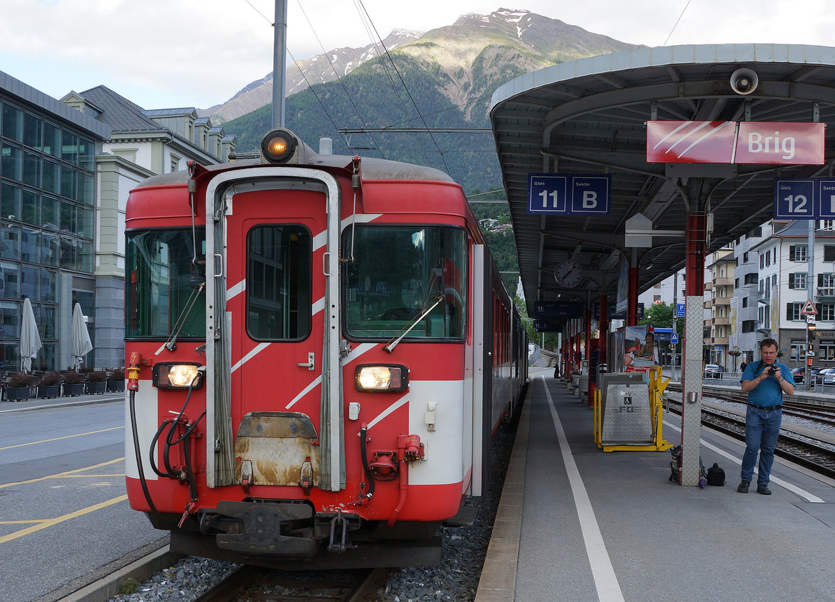 MGB: Bahnhof Brig mit Regionalzügen von Zermatt und nach Visp am späten Abend des 19. Juni 2016. Daniel Widmer von IG Schiene Schweiz wartete mit voller Konzentration auf die Ausfahrt des Regionalzuges nach Visp mit dem Deh 4/4 I 54 am Zugsschluss.
Foto: Walter Ruetsch