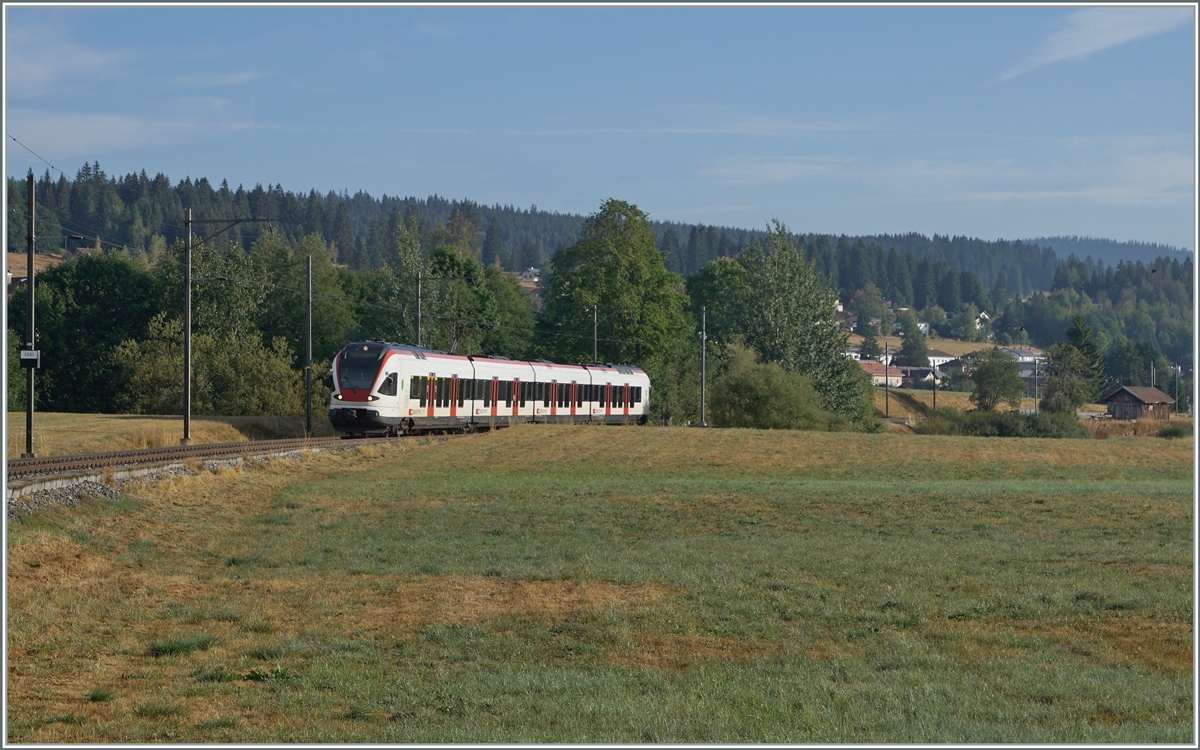 Nun haben auch wir unsere  Drei-Seen-Bahn : Die RER VAUD S2 von Aigle nach Le Brassus verbindet nicht nur recht kontrastreiche Landschaften, sie führt auch an drei Seen entlang: dem Lac Léman, dem Lac de Brent und dem Lac de Joux. A propos Wasser: Während der Genfersee durch die Rhone ins Mittelmeer mündet, entwässert sich die Orbe in die Nordsee doch der wenige Kilometer westlich von hier entspringende Doubs hingegen ins Mittelmeer.
Ganz rechts im Bild ist der von Peter schon 1967 fotografierte Schuppen zu erkennen. Zum Motiv selbst: Das Bild zeigt den SBB RABe 523 022-7 (RABe 523 94 85 0 523 022-7 CH-SBB) als S2 24216 von Aigle kurz vor der Ankunft in Le Brassus. 

15. August 2022
