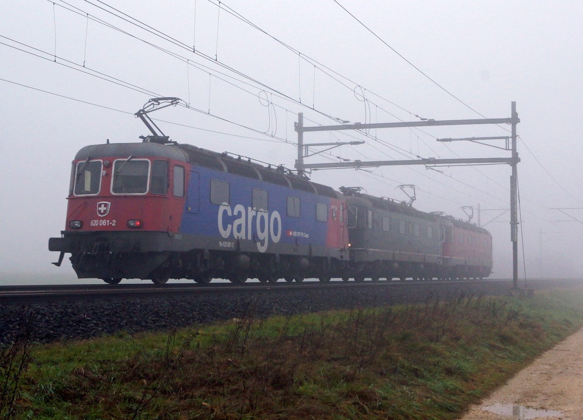 SBB: Infolge ausserordentlich schwerer Güterlast schleppten am 8. November die beiden Re 6/6 11 633 Eglisau und 11 623 Rupperswil den samstäglichen Güterzug nach Gerlafingen. Normalerweise reicht für diese Leistung eine Re 6/6. Aus diesem Grunde verkehrte der Lokzug ab Solothurn-HB mit drei Re 6/6 anstatt nur mit einer Doppeltraktion. Die Aufnahme von den drei Re 6/6 in drei verschiedenen Lackierungen (11 623 Rupperswil, 11 633 Eglisau und 620 061-2 Gampel-Steg) ist leider bei Niederbipp noch im dichten Herbstnebel entstanden.   
Foto: Walter Ruetsch 