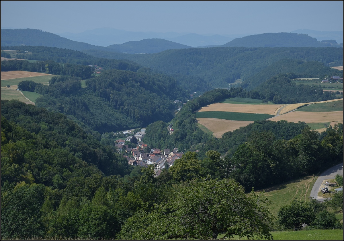 Umleiterverkehr auf dem Läufelfingerli. Die alte Hauensteinberglinie ist während der Gleisbauarbeiten bei Tecknau die Ausweichstrecke für nordwärts fahrende Züge. Hier sieht man schön die Hügel des Jura, im Hintergrund schon den Schwarzwald mit dem markanten Blauen. Erst bei genauem Hinsehen sieht man hier den Zug in der Bildmitte bei Bukten. Juli 2018. 

Der verantwortliche leitende Ingenieur Carl von Etzel war zuvor für den Bau der Geislinger Steige verantwortlich, später auch für die Brennerstrecke. Aber nicht nur der Erbauer, auch die Geologie und der frühe Bau als Bergstrecke lässt diese Linie als Schweizer Schwester der Geislinger Steige erscheinen.