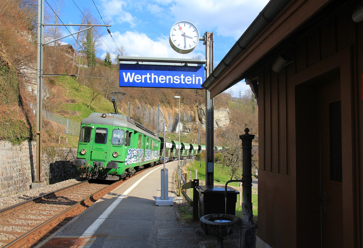 Werthenstein: Durchfahrt eines Kieszuges mit Makies-Triebwagen 576 049  Babette , ehemals SOB Triebwagen BDe 4/4 81 von 1959. Der kleine alte Brunnen am Bahnhof wirkt dabei ganz vertr�umt. 25.M�rz 2021  
