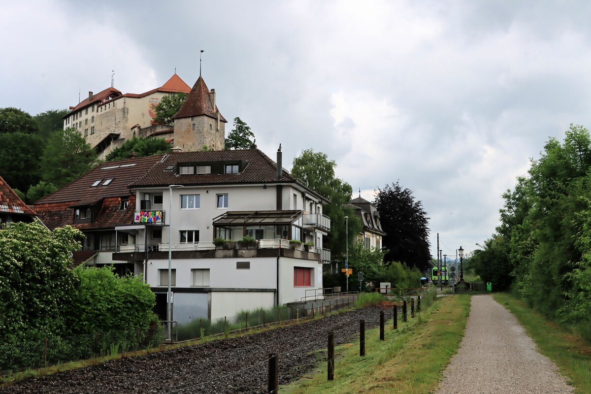 Wo früher die Sensetalbahn in den alten Bahnhof Laupen einfuhr sind jetzt die Schienen entfernt. Blick zur neuen Endstation im Hintergrund, mit einem BLS NPZ Pendelzug. Mächtig blickt die Burg von Laupen mit dem Berner Wappen über die Grenze nach Fribourg (jenseits desFlusses) hinüber. 8.Juni 2021 