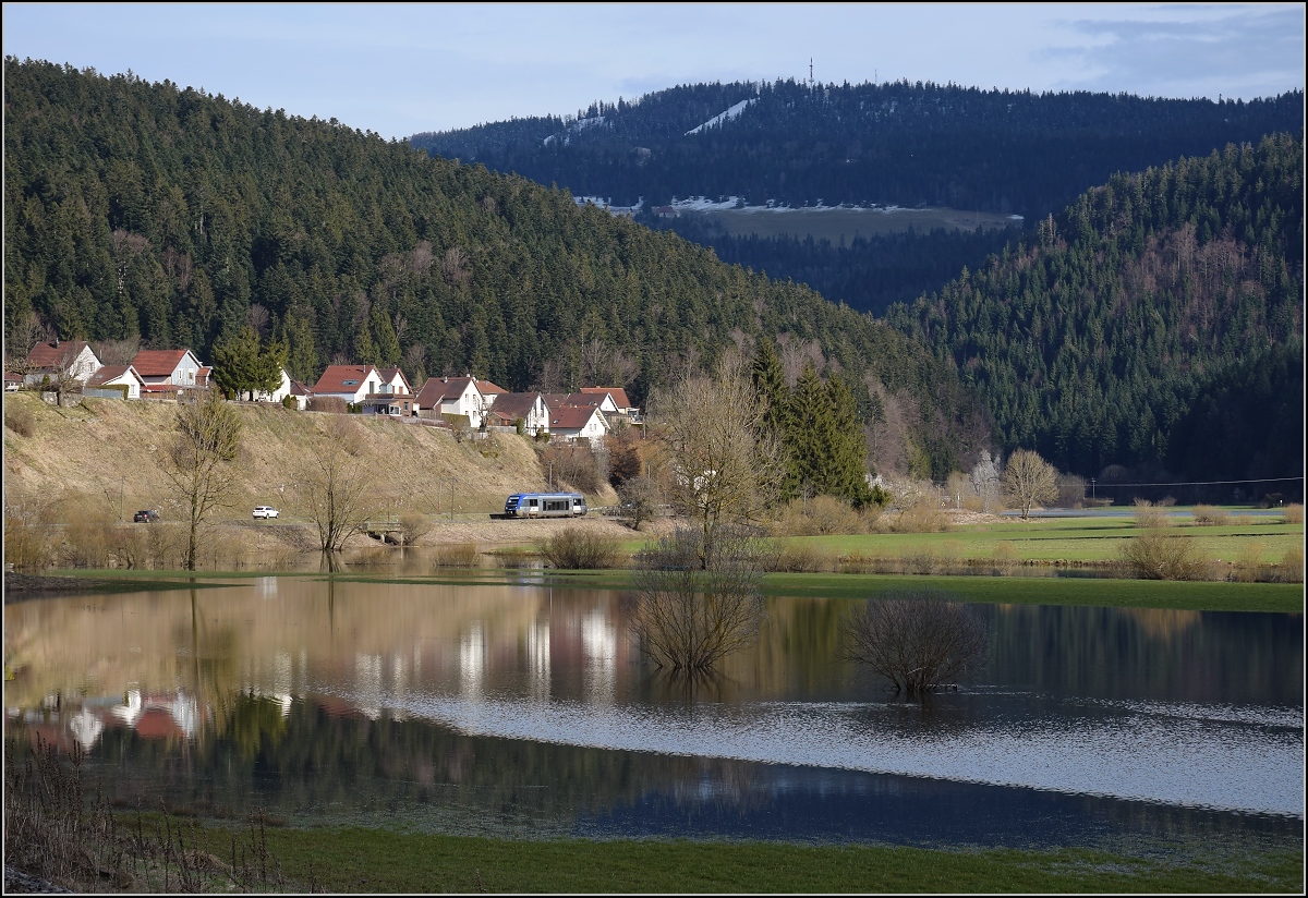 X 73754 bei der Einfahrt nach Morteau. Im Vordergrund der über die Ufer getretene Doubs. Im Hintergrund der 1283 m hohe Meix-Musy. Dahinter liegt das Hochtal von La Brevine in der Schweiz, auch bekannt als Schweizer Sibirien. Die tiefste offiziell gemessene Temperatur lag bei -42,8°C. April 2018.
