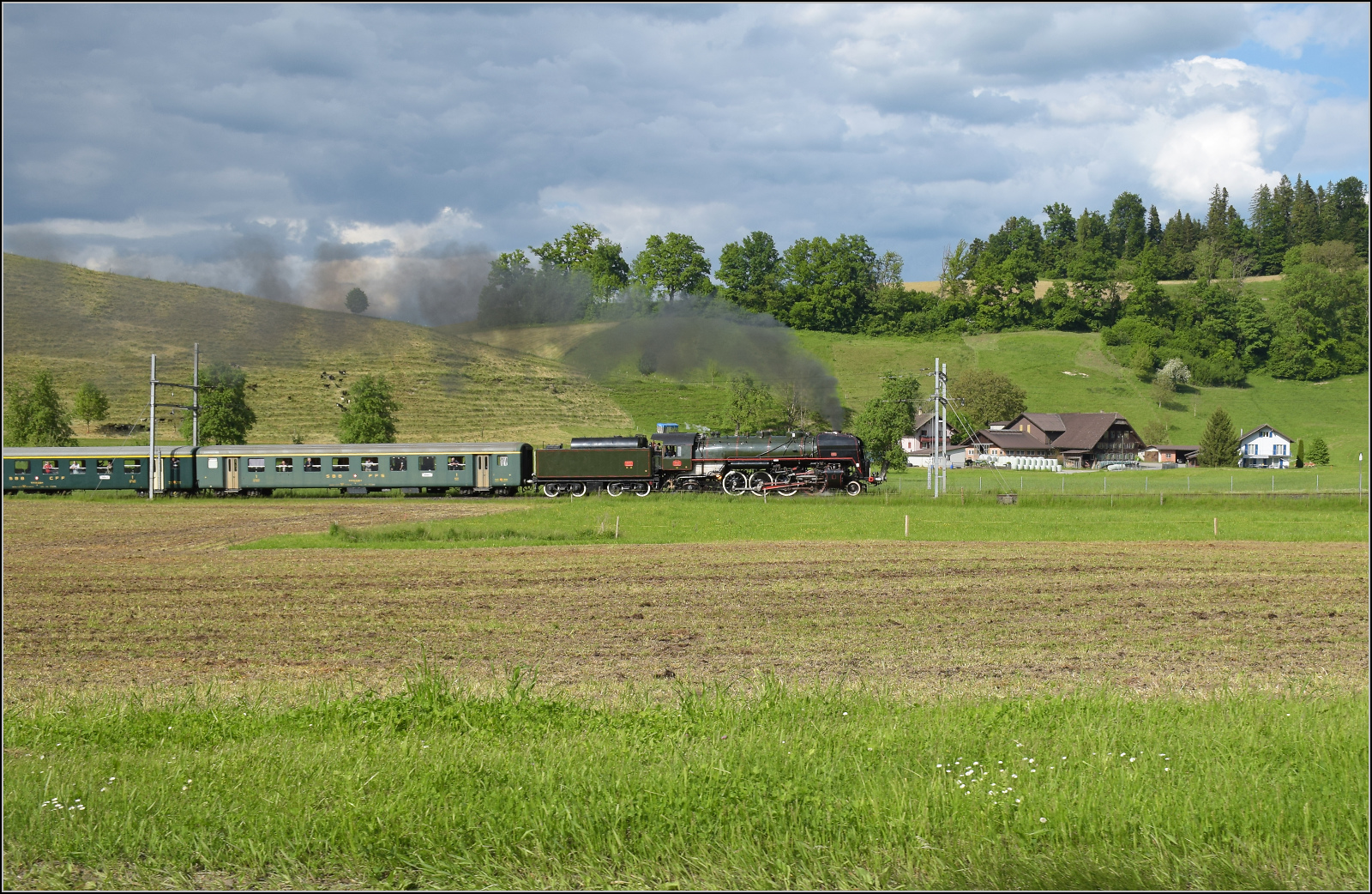 150 Jahre Emmentalbahn. 

141-R-1244 auf dem Rückweg von der grossen Emmentalrundfahrt anlässlich des Jubiläums. Am Ortsausgang Menznau findet die Sonne ein Wolkenloch, freie Sicht auf die Strecke und die Strasse ist ohne Verkehr. Menznau Hackbrett, Mai 2025.