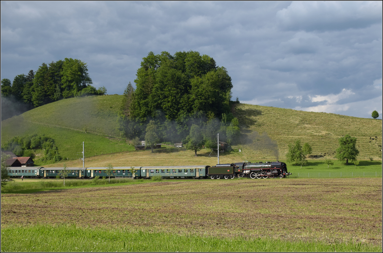 150 Jahre Emmentalbahn. 

141-R-1244 auf dem Rückweg von der grossen Emmentalrundfahrt anlässlich des Jubiläums. Am Ortsausgang Menznau findet die Sonne ein Wolkenloch, freie Sicht auf die Strecke und die Strasse ist ohne Verkehr, so begann eine kurze Parallelfahrt, wie man sie nur selten durchführen kann. Mai 2025. 