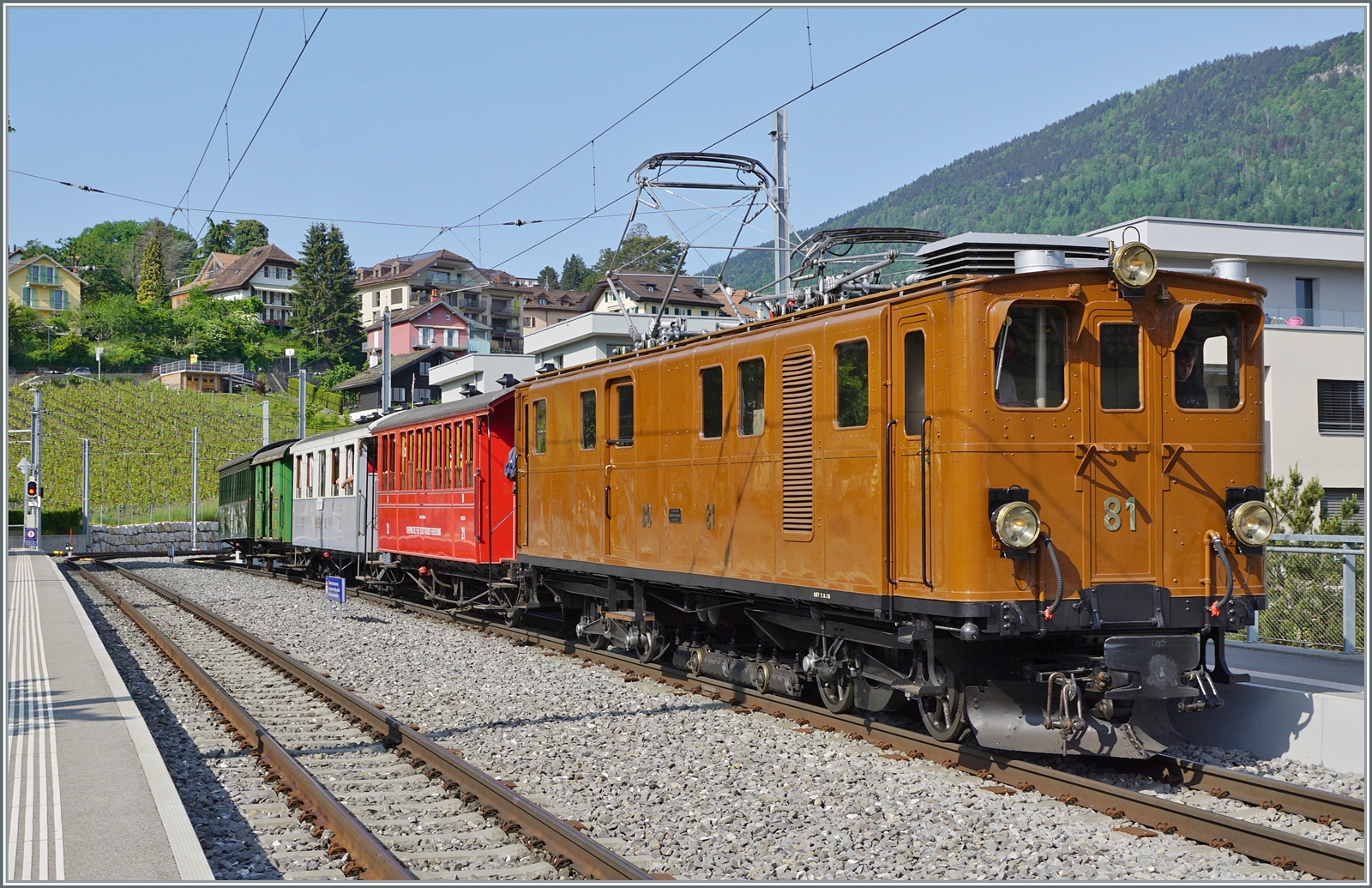 Die Bernina Bahn RhB Ge 4/4 81 der Blonay-Chamby Bahn ist mit ihrem recht gut besetzten Riviera Belle Epoque Zug von Chaulin auf dem Weg von Chaulin nach Vevey und wartet in St-Légier Gare auf den Gegenzug.

28. Mai 2023 