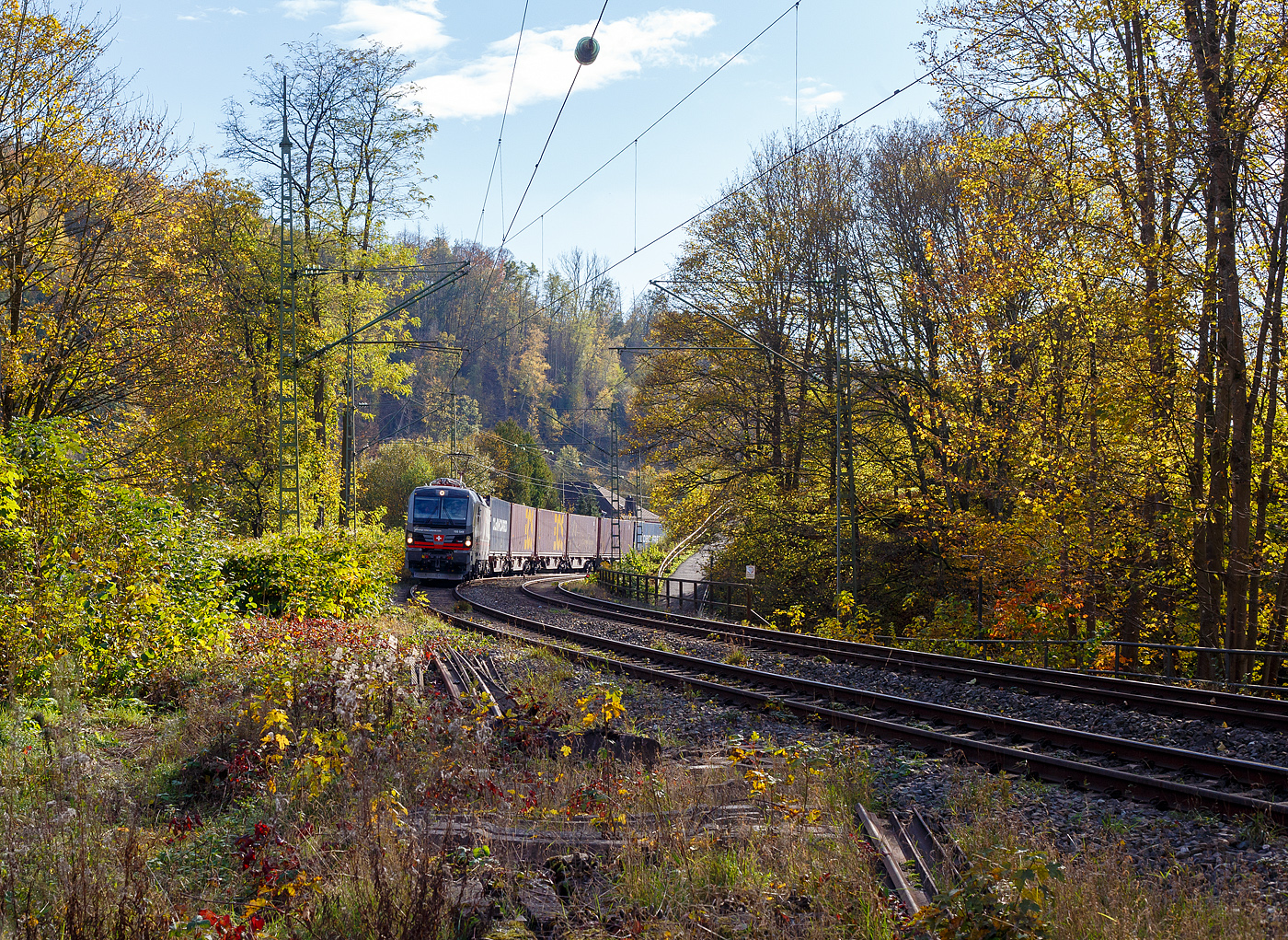 Ein fast fabrikneuer SIEMENS XLoad-Vectron, gerade mal 4 Wochen alt.
Die an die SBB Cargo International AG vermietete 193 539 mit XLoad  Duomo Milano  (91 80 6193 549-3 D-SIEAG) der SüdLeasing GmbH, Stuttgart (eingestellt in Deutschland durch Siemens) fährt am 29.10.2024 mit einem KLV-Zug, durch Kirchen (Sieg) in Richtung Siegen.

Die Multisystemlokomotive Siemens Vectron MS wurde 2024 von Siemens Mobilitiy in München-Allach unter der Fabriknummer 23595 gebaut und am 25.09.2024 ausgeliefert. Sie wurde in der Variante A40-1a ausgeführt und hat so die Zulassung für Deutschland, Österreich, die Schweiz, Italien, die Niederlande und Belgien (D / A / CH / I / NL / B). Sie verfügt über eine Leistung von 6,4 MW (160 km/h) und ist neben den nationalen Zugsicherungssystemen mit dem Europäischen Zugsicherungssystem (ETCS  BL3) ausgestattet. Zudem ist sie mit der neuen Ausrüstungspaket XLoad ausgestattet. 

Das neue XLoad Ausrüstungspaket für Vectron:
XLoad ist ein Ausrüstungspaket für Vectron, welches künftig mitbestellt, aber auch bei bereits ausgelieferten Vectron Loks nachgerüstet werden kann. Das Feature verbessert die Reibwertausnutzung und ermöglicht dadurch höhere Anhängelasten. Zudem reduzieren die Fahreigenschaften, die das Feature bewirken, den Verschleiß von Rad und Schiene.

Aktuell sind die Schweizer Vectron-Lokomotiven (SBB Cargo und BLS Cargo) in der Regel in Doppeltraktion unterwegs. Die Steigungen und Rampen der Schweizer Berge sind vor allem bei schlechten Witterungsbedingungen nicht ohne. Eine Lokomotive muss auch bei geringerem Schlupf genügend Traktion auf die Schienen bringen, um alle Güter sicher und zuverlässig ans Ziel zu bringen. Ein effizienter Weg aus dieser «Misere» ist die für Vectron entwickelte Zusatz-Funktion «XLoad». Den erfolgreichen Beweis trat eine SIEMENS Testlokomotive im Frühjahr 2022 bei der SBB Cargo International und bei der BLS Cargo eindrücklich an. 

Für SBB Cargo International bewies die Test-Lokomotive am Bözberg und für BLS Cargo an der Nordrampe des Lötschbergs ihre enorme Zugkraft. 
Vectron meisterte im Frühjahr 2022 die lange 12‰-Steigung des Bözbergs mit einer Anhängerlast von 2.000 Tonnen bravourös. Bei den nächtlichen Testfahrten zeigte sich eindrücklich die enorme Zugkraft der Lokomotive. 

Am Lötschberg wurden bei der BLS Cargo steigungsmäßig noch ein paar Promille draufgepackt. Mit 1.020 Tonnen im Gepäck bewältigte die Vectron-Lokomotive mit XLoad-Feature die 27‰-Steigung der Nordrampe ebenfalls meisterlich. Und auch diverse Anfahrtsversuche absolvierte der mit dem XLoad-Feature aufgerüstete Vectron problemlos. 

So bestellte die SüdLeasing GmbH (Stuttgart) im Auftrag der SBB Cargo International jüngst 20 Vectron Lokomotiven mit XLoad bei SIEMENS.