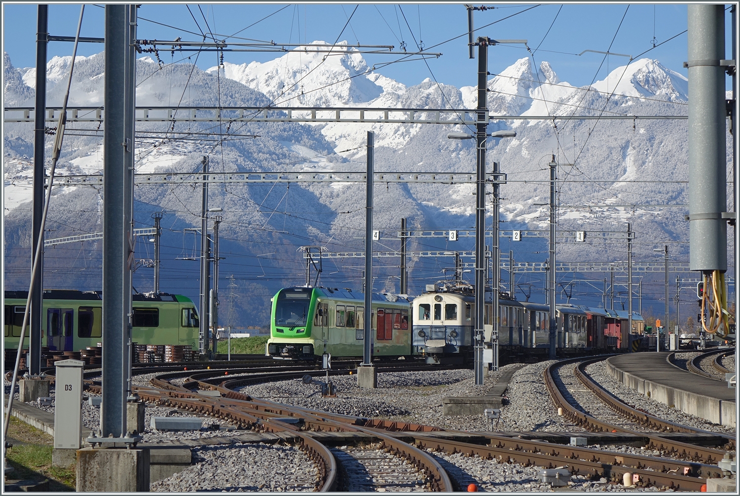 Ein Tele-Blick ins TPC D�p�t in Aigle, welcher neben den frisch verschneiten Bergen im Hintergrund, besonders den neuen TPC/ASD ABe 4/8 471 (Baujahr 2023) neben dem ASD BCFe 4/4 N� 1  TransOrmonan  (Baujahr 1913) im Visier hat.

3. Dez. 2023