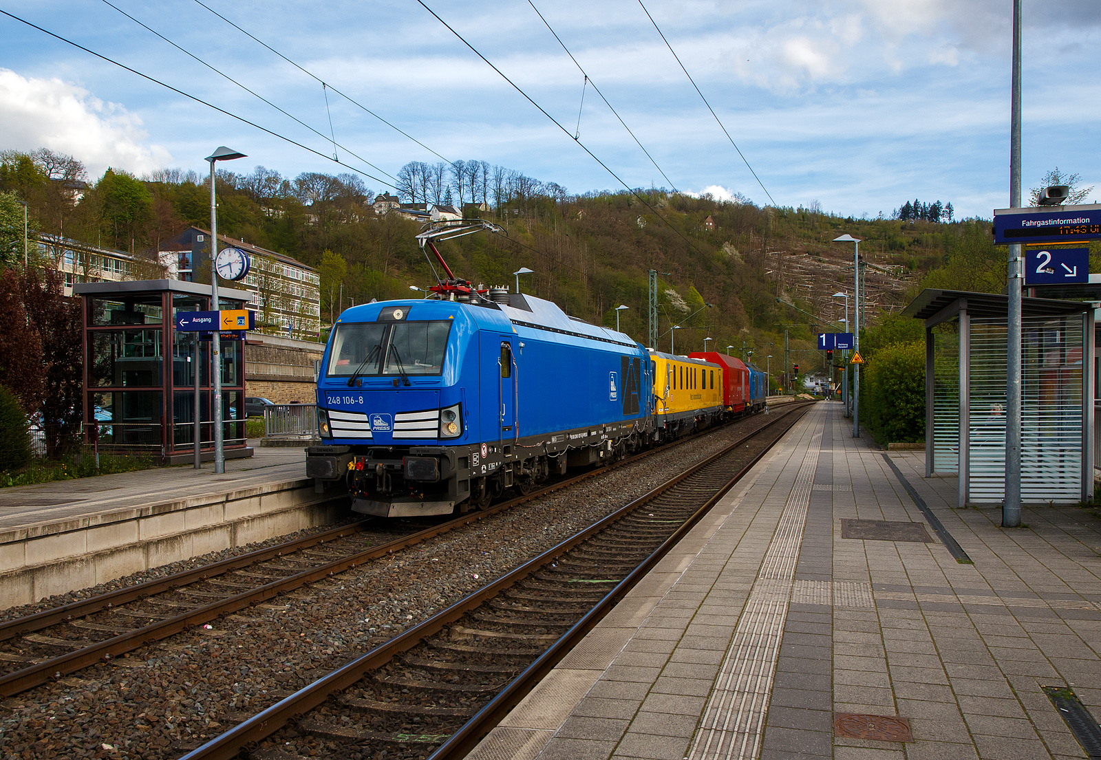 In einer ungewöhnlichen Komposition (im Sandwich zweier SIEMENS Vectron Dual Mode) fährt ein Schienenprüfzug (SPZ 3), auf Prüffahrt (der Messwagen ist auf die Schiene absenkt) am 30.04.2023 durch den Bahnhof Kirchen an der Sieg in Richtung Siegen. 

Die vierteilige Komposition bestand aus:
• Der SIEMENS Vectron Dual Mode der 248 027-5 (90 80 2248 027-5 D-PRESS) alias 248 106-8 der PRESS (Eisenbahnbau- und Betriebsgesellschaft Pressnitztalbahn mbH, Jöhstadt).
• Dem Messwagen SPZ-STW (STW steht für Steuerwagen) 720 301(99 80 9360 006-7 D-DB) der DB Netz AG (Netz Instandhaltung/Fahrwegmessung).
• Einem Hilfszug-Wagen (Nummer unbekannt) der DB Netz AG (Notfalltechnik).
• Und der SIEMENS Vectron Dual Mode der 248 026-7 (90 80 2248 026-7 D-PRESS) alias 248 105-9 der PRESS (Eisenbahnbau- und Betriebsgesellschaft Pressnitztalbahn mbH, Jöhstadt).

Die Energieversorgung vom Messwagen und dem Hilfszug-Wagen erfolgte von den Loks (spartanisch) über außenverlegte Kabel, zudem waren beide Loks über eine außenliegende Steuerleitung verbunden. Normalerweise ist der Schienenprüfzug ein zweiteiliger Messtriebwagen, bestehend aus Trieb- (ATW - 719 301) und einem Steuerwagen (STW - 720 301), siehe u.a. http://hellertal.startbilder.de/bild/Deutschland~Unternehmen~DB+Netz+AG/773623/der-plasser--theurer-schienenpruefzug-der.html Warum es nun diese Komposition ist, das ist mir nicht bekannt, vielleicht setzt man nun noch mehr auf E-antrieb.

Der Schienenprüfzug wurde 2015 von Plasser & Theurer in Linz (A) unter der Fabriknummer 6003 (SPZ-STW) gebaut. Um Schäden am Oberbau frühzeitig zu erkennen, setzt die Deutsche Bahn AG verschiedene Prüfzüge der Baureihen 719 und 720 ein. Mittels zweier zerstörungsfreier Prüfverfahren werden die Schienen auf Schädigungen untersucht. Bei der Ultraschallprüfung können Materialfehler durch Materialermüdung innerhalb der Schiene bis zum Schienenfuß erkannt werden. Mit der Wirbelstromprüfung wird der Schienenkopf geprüft.

Die beiden SIEMENS Vectron Dual Mode wurden 2022 von SIEMENS in München-Allach, unter den Fabriknummern 23168 und 23169, gebaut und an die PRESS - Eisenbahnbau- und Betriebsgesellschaft Pressnitztalbahn mbH in Jöhstadt geliefert. Die beiden Vectron DM haben die Zulassung in Deutschland für eine Höchstgeschwindigkeit 160 km/h.

Der Vectron Dual Mode vereint die Vorteile einer vollwertigen Diesellokomotive mit denen von elektrischen Lokomotiven. Dank des leistungsstarken Dieselantriebs sowie der Ausstattung für die Nutzung der Fahrleitung kann man jederzeit flexibel auf die Traktionsanforderungen reagieren. So bleibt man immer in Bewegung, egal ob mit oder ohne Fahrdraht. Wo ein Fahrdraht ist, sollte man ihn nutzen. Denn der Betrieb unter Oberleitung ist im Vergleich zum Dieselbetrieb deutlich kosteneffizienter und umweltfreundlicher. Doch weil es in Deutschland noch lange Zeit Strecken geben wird, die nicht vollständig elektrifiziert sind, fahren viele Diesellokomotiven unter Fahrdraht weiter. Das ist aber ökonomisch und ökologisch wenig sinnvoll. Dies ist hier ein Beispiel einer echten Alternative.