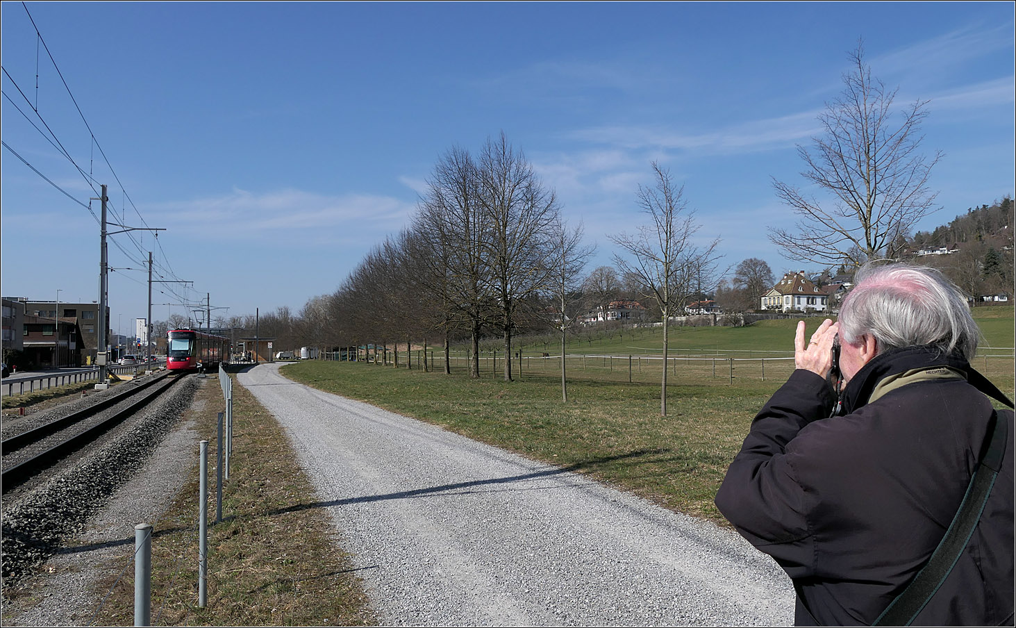 Mit Peter unterwegs durch Bern - 

Peter beim Fotografieren der Tramlink bei der Haltestelle Siloah zusammen mit dem kleinen Schlösschen Gumligen. Von Peter habe ich schon manche Aufnahmen gesehen, bei der Bahn und Motiv an der Strecke auf diese Weise zusammengebracht werden, indem die Bahn sehr am Bildrand  
platziert wird. Hier habe habe ich dass übernommen, mit Peter als weiterem Motiv mit dem Schlösschen Gumligen direkt links neben Peter.

07.03.2025