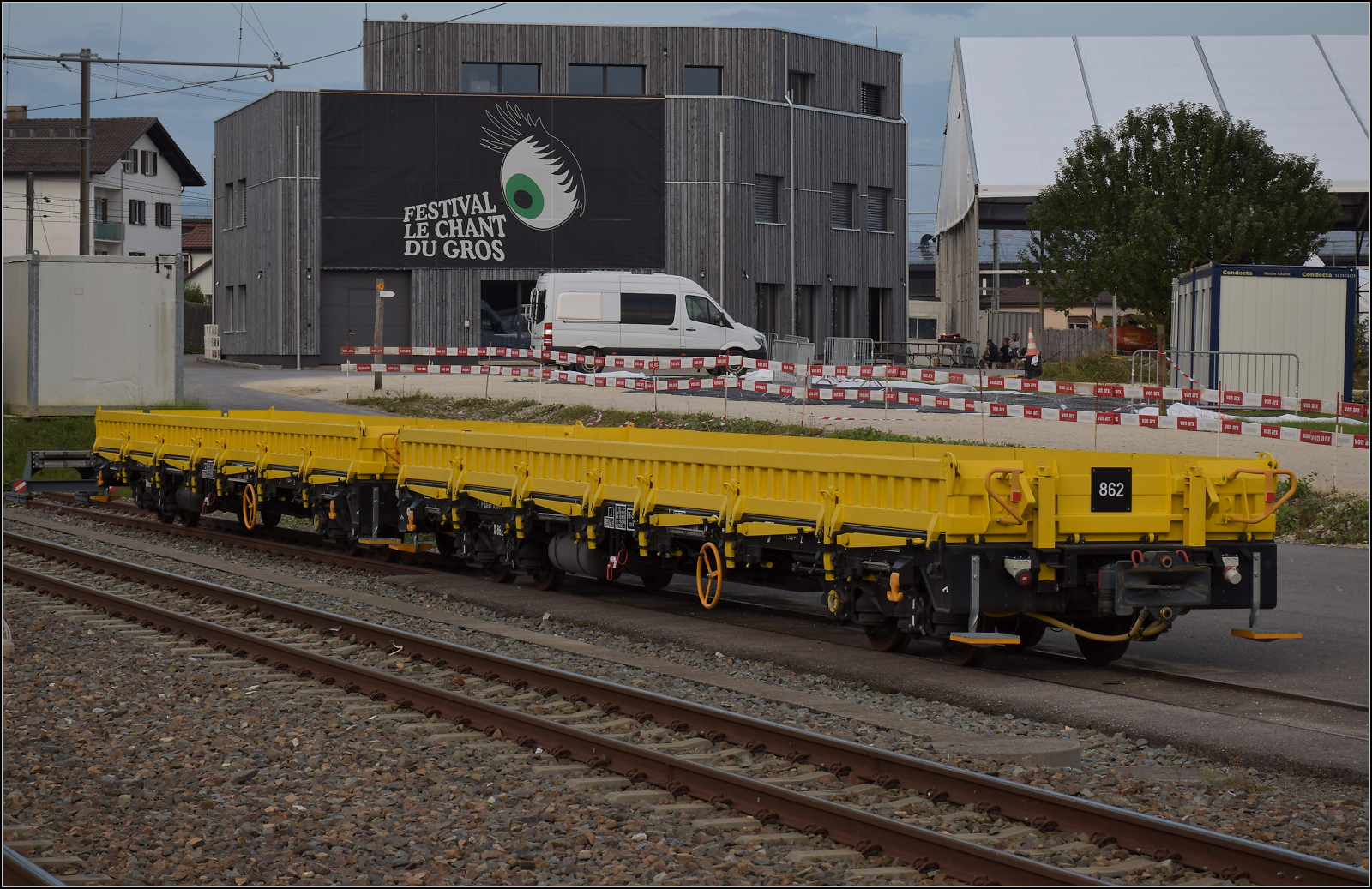 Neubaug�terwagen der CJ. Nur drei Jahre alt sind die Flachwagen X 862 und X 863. Im Hintergrund sind die Festhallen des Chant du Gros-Festival in Le Noirmont zu sehen. August 2024.