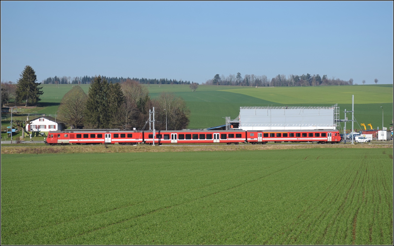 Noch ein bisschen Ajoie.

RABe 567 184 der CJ f�hrt an der Kulisse von Alle vorbei, wie man sieht, ist die neue, h�ssliche Kl�tzchenbauweise nunmehr auch in diesem etwas vertr�umten Fleckchen Schweiz im Vormarsch. Februar 2023.