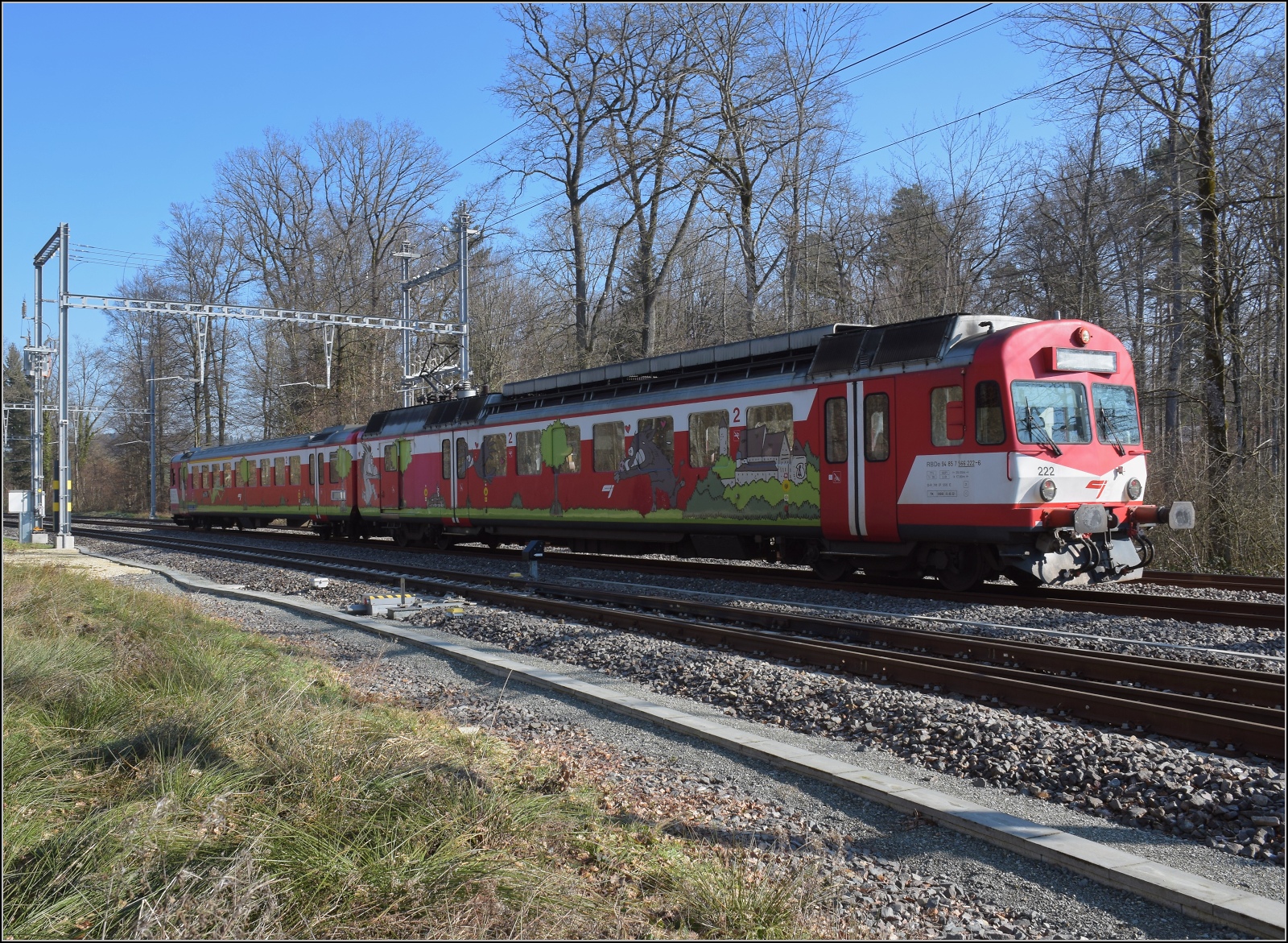 Noch ein bisschen Ajoie.

Versteckt im Güterbahnhof von Alle steht aufgerüstet ein Schmankerl. RABe 566 222 der CJ ist der NPZ-Vorläufer und immer noch aktiv in Notfällen. Herzig sind die Motive, die die angebundenen Orte Bonfol, Vedlincourt, Alle und Porrentruy. Dabei entspringt der Frosch offenbar den Fischteichen von Bonfol und die Wildsau dem Stadtwappen von Porrentruy. Februar 2023.