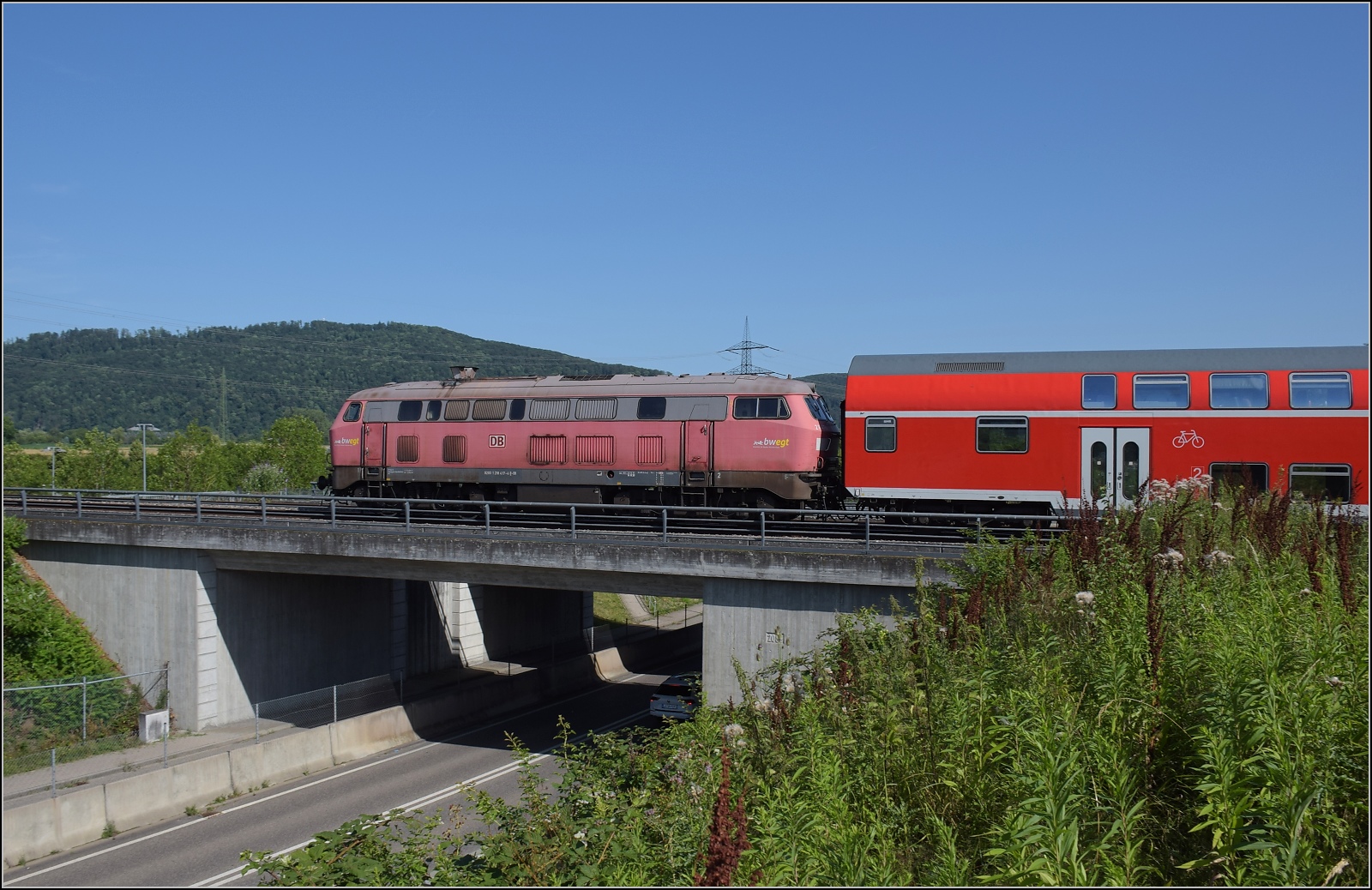 Nur für kurze Zeit: Fast historischer Grossdiesel an zwei Stellen in der Schweiz. Aus Basel bad Bf brummt 218 417 vorbei mit Ziel Friedrichshafen. Ihr Motor ist weithin hörbar, aber direkt neben der Strecke ist sie eine dahingleitende Flüsterlok. Hingegen das Rumpelstilzchen alias Heulsuse alias BR 245 hat zwar leise Dieselmotoren, benimmt sich ansonsten aber eher wie eine Gleisstopfmaschine... Warmbach, Juli 2023.
