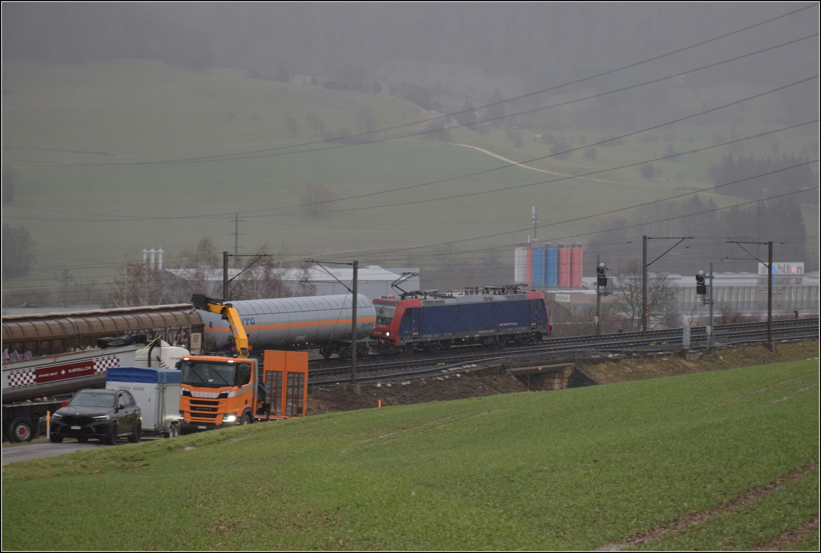 Schlechtwetter und ein Baustellendrama bei Frick. 

Re 484 015 auf dem Weg zum B�zberg. Die Traxxe MS2 der Baureihe Re 484 sind nunmehr das letzte verbliebene Mitglied der verschiedenen Traxx-Baureihen bei den SBB. Als Sonderbaureihe MS2 ohne das e d�rfte wohl ein Verkauf schwerfallen, da die Zulassung sich nur auf die Schweiz bezieht. Im UIC-Raster ist mittlerweile auch das I verschwunden, so dass eine Zulassung in anderen L�ndern wohl nachtr�glich kaum noch m�glich sein wird. Aber nicht nur schlechte Aussichten f�r diese Lokbaureihe, wir k�nnen erst einmal nicht den einzigen nicht gesperrten Ausgang von diesem Ort nicht mehr nutzen, weitere Fotos machen bei dem Regen und der Entfernung vom Gleis auch nur noch bedingt Sinn... Februar 2026.