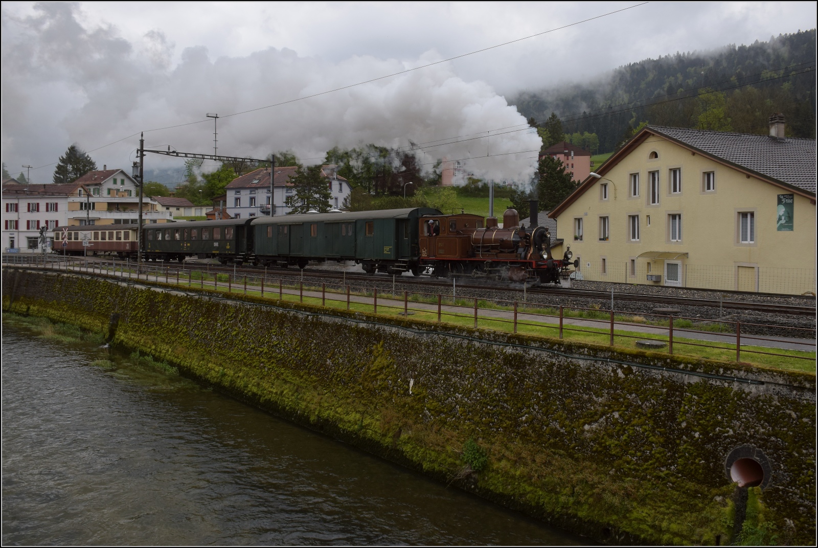 Vapeur Val-de-Travers: Train  Au fil de l'Areuse .

E 3/3 8511 in Couvet mit Areuse. Mai 2023.