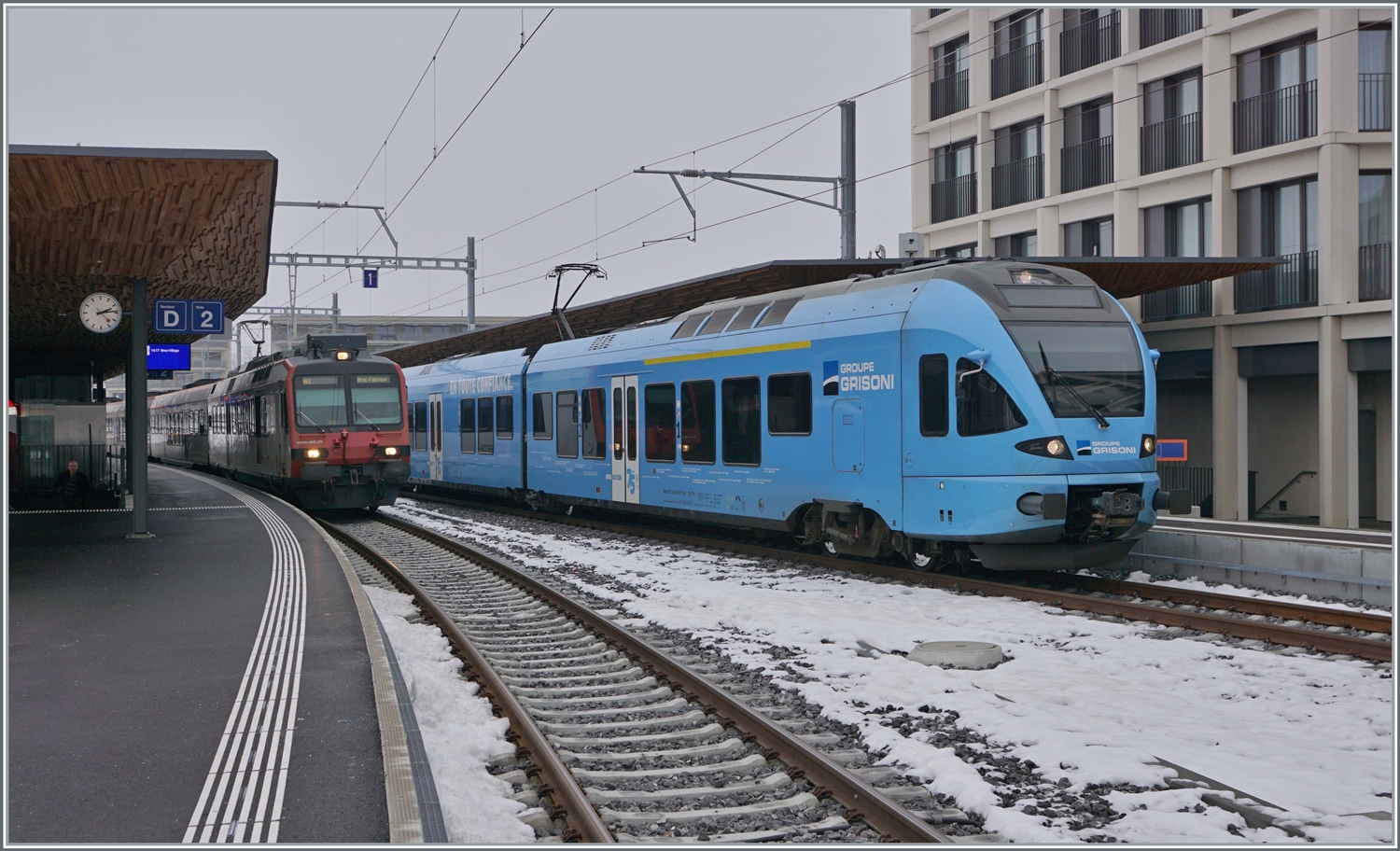 Während der gefällige TPF Flirt RABe 527 198  Groupe Grisoni  in Bulle endet, fährt der SBB RBDe 560 weiter; wobei sich Bahnhofsanzeige und die Anzeige am Zug nicht ganz einig sind wohin die Fahrt geht. Kleine unstimmige Details in den ersten Tagen nach der Aufnahme des Verkehrs auf der umgespurten Strecken Bulle - Broc VILLAGE. 

15. Dez. 2022