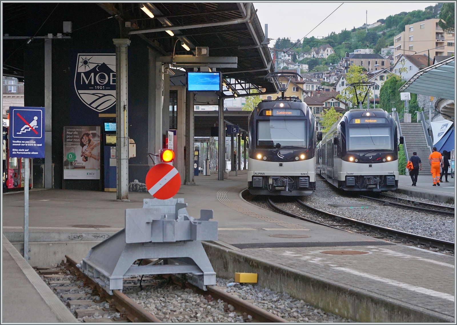 Während der MOB  Alpina  Be 4/4 9203 mit seinem Panoramic Zug auf die Abfahrt nach Zweisimmen wartet, steht ein CEV MVR ABeh 2/6 7506 (und ein weiterer) als Regionalzug nach Montbovon in Montreux. Zudem gibt es im Bild weiter Details zu sehen, wie z.B das Schild, welches verbietet an Bahnsteigkanten zu sitzen. 

23. Mai 2023