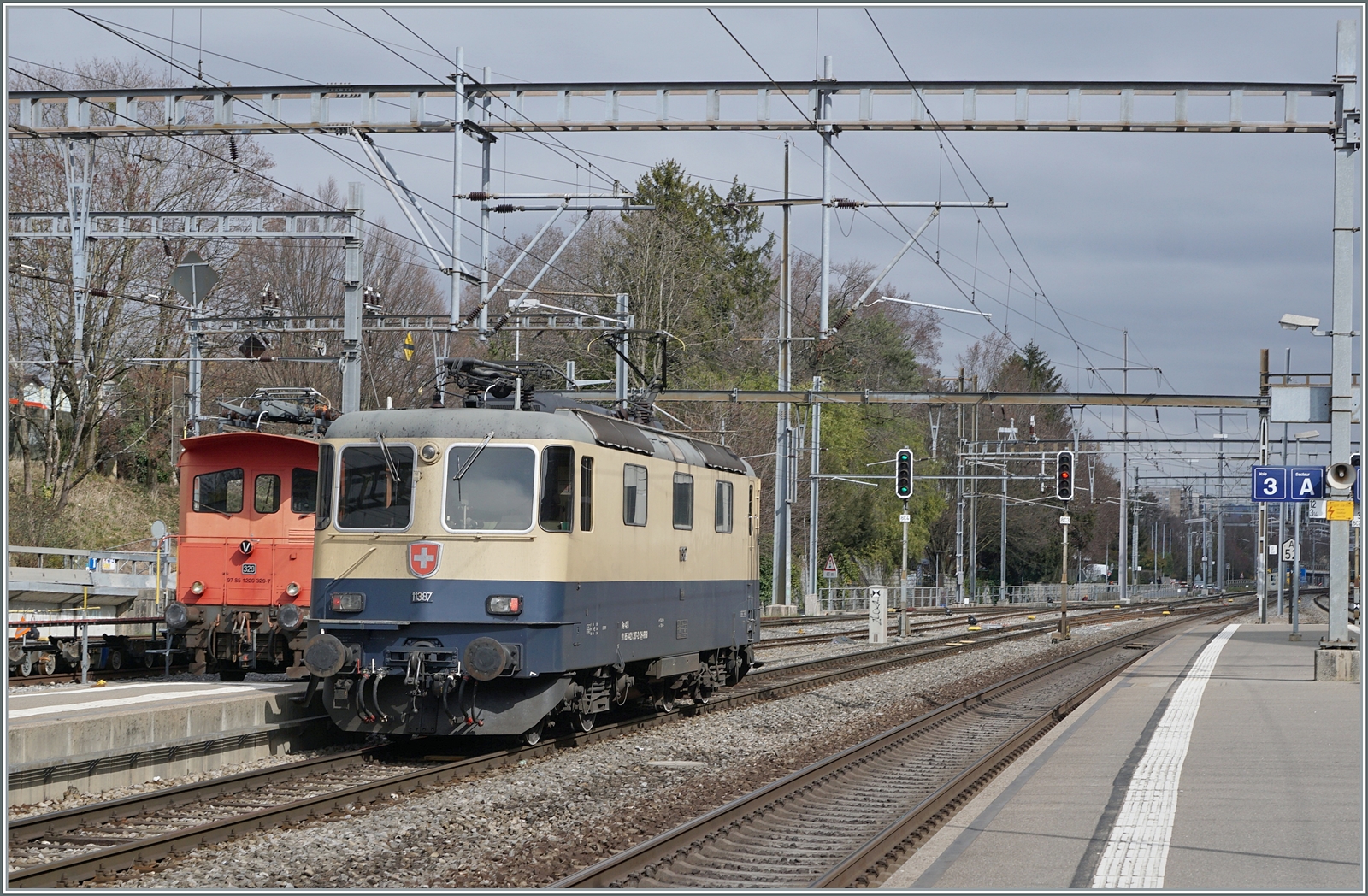 Wettermässig waren meine bisherigen Bilder der IRSI  Rheingold  Re 4/4 II 11387 (Re 421 387) bei der BAM eher von lichtarmen Verhältnissen geprägt. Doch kurz um die Mittagszeit erhellten ein paar Sonnenstrahlen die Szenerie, als die IRSI  Rheingold  Re 4/4 II 11387 (Re 421 387), die eine Kieszug nach Morges gebracht hatte, diesen stehen liess und nun, wie zu sehen, in Richtung Lausanne Triage fährt, um dort einen weiteren Kieszug abzuholen.

4. März 2024 