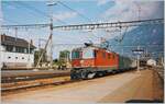 Die SBB Re 4/4 II 11187 verlässt mit einen Schnellzug den Bahnhof von Martigny. Der Schnellzug ist auf der Fahrt von Brig nach Basel SBB via Lausanne und Biel/Bienne. Analogbild vom August 1995